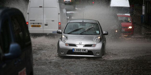 Traffic drives through a flooded road in Lewisham in south east London as a third of a month's rain could fall in just a few hours today as torrential downpours and thunderstorms hit parts of the UK.