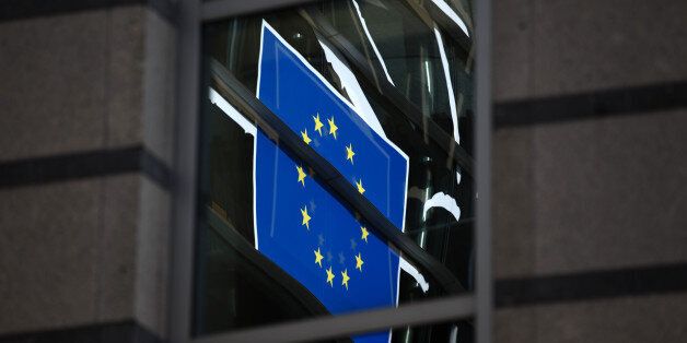 The flag of the European Union (EU) reflects off windows at the parliament building in Brussels, Belgium, on Thursday, Sept. 26, 2013. The U.K. challenged European Union caps on banker bonuses at the bloc's highest court, marking its third court battle against the EU as the region overhauls its financial rules. Photographer: Jasper Juinen/Bloomberg via Getty Images