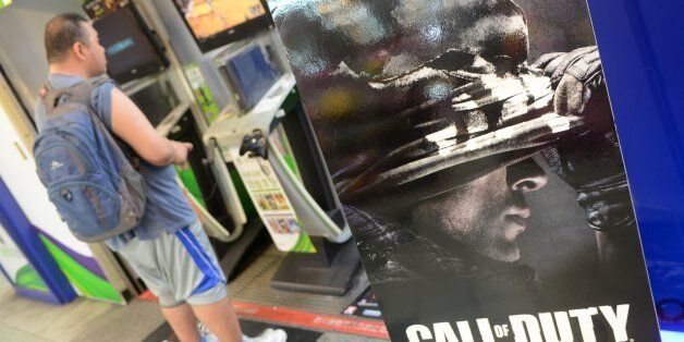 A local resident plays video games next to a advertising sign of the videogame 'Call of Duty' in Taipei on November 5, 2013. Hordes of excited gamers descended on shops across the globe to get their hands on the latest release from the blockbusting 'Call of Duty' video game franchise. AFP PHOTO / Sam Yeh (Photo credit should read SAM YEH/AFP/Getty Images)