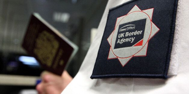 File photo dated 23/11/2009 of a UK Border Agency officer checking a passport as Britain is at risk of harbouring war criminals and terrorists due to poor decisions made by border officials, an influential group of MPs has warned.