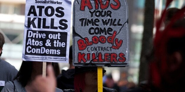 Protesters carry placards during a protest against multinational IT firm and Paralympics sponsor Atos outside the company's head office in London on August 31, 2012. Protesters are outside Atos to protest there involvement in the tests on incapacity benefit claimants that has been awarded to them by the Department of Work and Pensions. Disabled and anti-cuts campaigners have been rallying as they claim the tests for people on disability by Atos are 'damaging and distressing'. AFP PHOTO / ANDREW