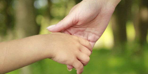 a parent holds the hand of a...