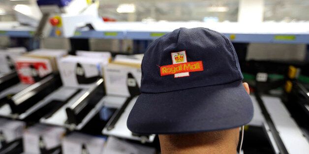 A logo sits on the cap of a Royal Mail Plc employee as he collects pre-sorted letters for delivery from a sorting machine at the company's Mount Pleasant postal sorting office in London, U.K., on Tuesday, Feb. 11, 2014. Royal Mail, the U.K. postal service that sold shares in an initial public offering last year, said like-for-like sales gained 2 percent in the first nine months of the year boosted by parcel deliveries. Photographer: Chris Ratcliffe/Bloomberg via Getty Images