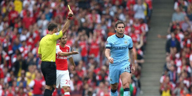 Referee Mark Clattenburg (left) shows the yellow card to Manchester City's Frank Lampard (right)