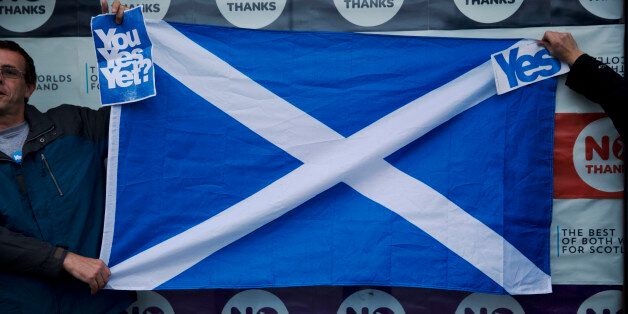 Two Scottish independence referendum Yes supporters hold a Scottish Saltire flag up outside the