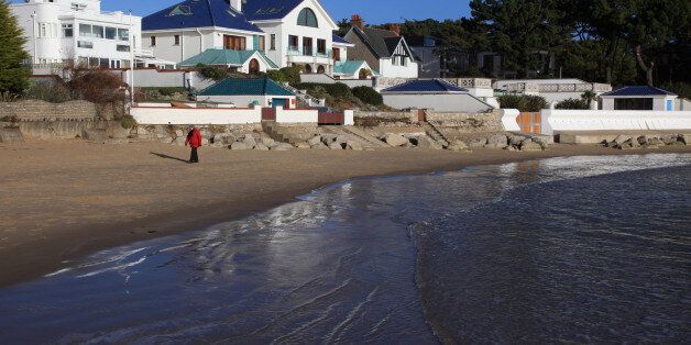 People walk on the beach in the exclusive residential area of Sandbanks on in Poole, England
