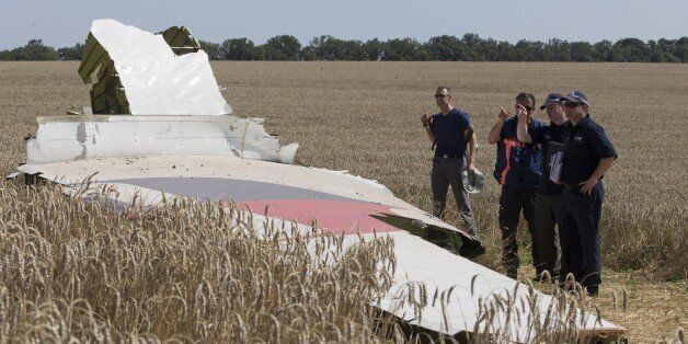 Australian and Dutch investigators examine a piece of the Malaysia Airlines Flight 17 plane, near the village of Hrabove, Donetsk region, eastern Ukraine Friday, Aug. 1, 2014. The investigators from the Netherlands and Australia plus officials with the Organization for Security and Cooperation in Europe traveled from the rebel-held city of Donetsk in 15 cars and a bus to the crash site outside the village of Hrabove. Then they started setting up a base to work from at a chicken farm. The investi
