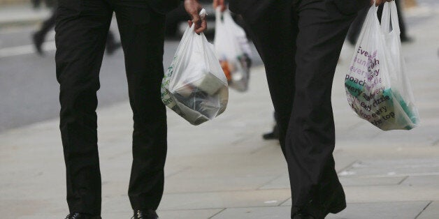 Male customers are seen carrying Tesco branded shopping bags after leaving a Tesco Metro supermarket store, operated by Tesco Plc, in London, U.K., on Monday, Sept. 22, 2014. Tesco Plc, Britain's biggest supermarket chain, started a probe of accounting practices and suspended its U.K. chief after overstating its first-half profit estimate. Photographer: Simon Dawson/Bloomberg via Getty Images