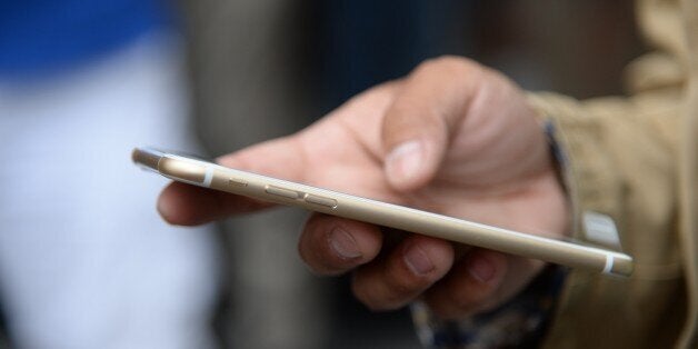 Tony Zhan checks out his new iPhone 6 Plus outside the Apple store in Pasadena, California on the first day of sale, September 19, 2014. The California tech giant has said more than four million pre-orders were received in the 24 hours after the sale of the new devices was announced. AFP PHOTO / ROBYN BECK (Photo credit should read ROBYN BECK/AFP/Getty Images)