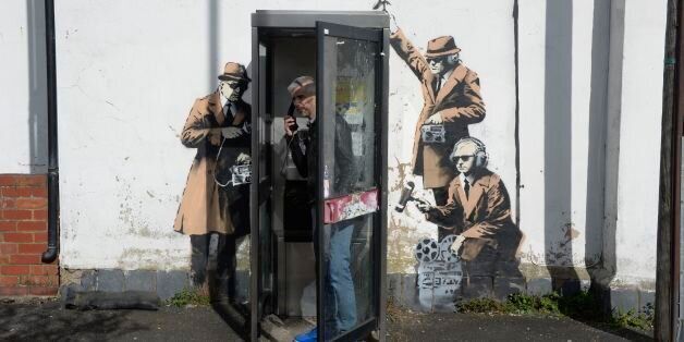 The new graffiti street art piece, suspected of being a Banksy, which appeared on the side of a house on Fairview Road adjacent to St. Anne's Terrace, Cheltenham. The artwork, which shows three figures listening into a conversation at a telephone box, is just a few miles away from Government Communications Headquaters (GCHQ), which is responsible for providing signals intelligence and information assurance to the British Government and Armed Forces.