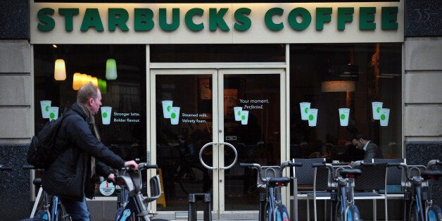 TO GO WITH AFP STORY BY RUTH HOLMES A man parks his hire bicycle outside a branch of Starbucks in central London on February 1, 2013. Despite pledging to pay millions of pounds in extra tax in Britain, Starbucks faces a battle to restore its reputation over its fiscal stance, with analysts saying the offer is 'too little too late'. AFP PHOTO / CARL COURT (Photo credit should read CARL COURT/AFP/Getty Images)