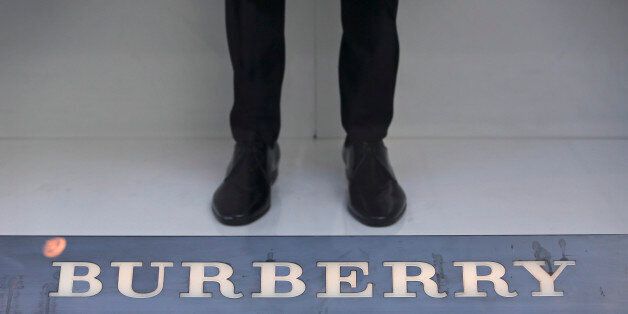 A mannequin stands beyond a logo in the window display of a Burberry Group Plc luxury clothing store on New Bond Street in London, U.K., on Tuesday, Oct. 15, 2013. Burberry named Christopher Bailey as chief executive officer to succeed Angela Ahrendts who will leave in 2014 to work as a senior vice president at Apple Inc. Photographer: Chris Ratcliffe/Bloomberg via Getty Images