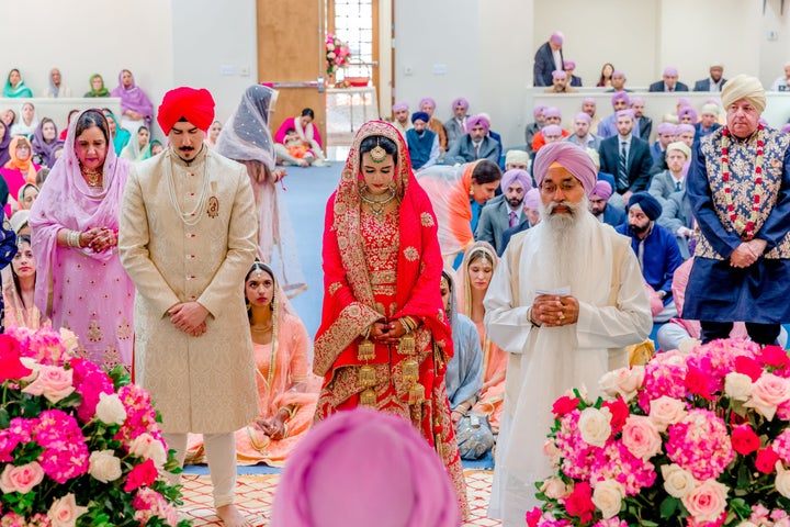 The author and her husband at the beginning of their Sikh wedding ceremony, standing with their parents for a prayer.