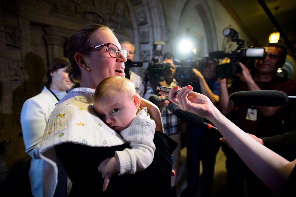 Democratic Institutions Minister Karina Gould speaks with reporters in Ottawa as she carries her baby Oliver following a cabinet meeting on May 22, 2018.
