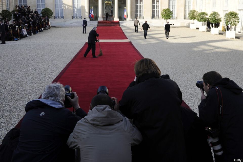 An employee sweeps up the red carpet as 