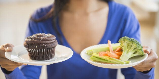 Mixed race woman choosing vegetables or cupcake