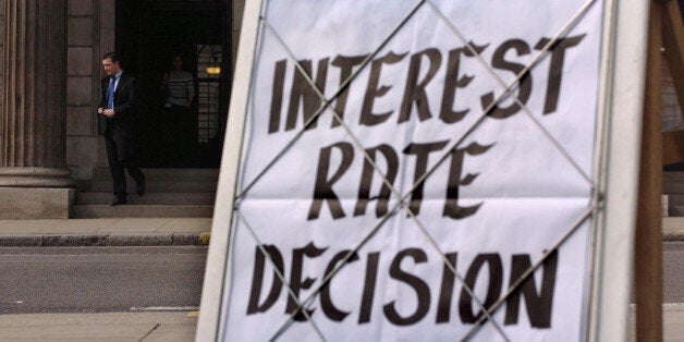 A newspaper board features news concerning the announcement by the Bank of England of a cut in interest rates from 4.75\% to 4.5\%, as a man walks out of the Bank of England in the City of London, Thursday August 4, 2005. The Bank of England's move to reduce its base rate to 4.5\% was also welcomed by industry leaders, following the UK economy's worst growth rate in 12 years. See PA Story ECONOMY Rates. PRESS ASSOCIATION Photo. Photo credit should read: Johnny Green/PA