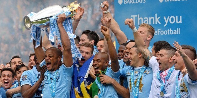 Manchester City's Belgian midfielder Vincent Kompany celebrates with the trophy after his team won the Premiership title following their victory in the English Premier League football match between Manchester City and West Ham United at the Etihad Stadium in Manchester on May 11, 2014. AFP PHOTO/ANDREW YATESRESTRICTED TO EDITORIAL USE. No use with unauthorized audio, video, data, fixture lists, club/league logos or live services. Online in-match use limited to 45 images, no video emulation. No