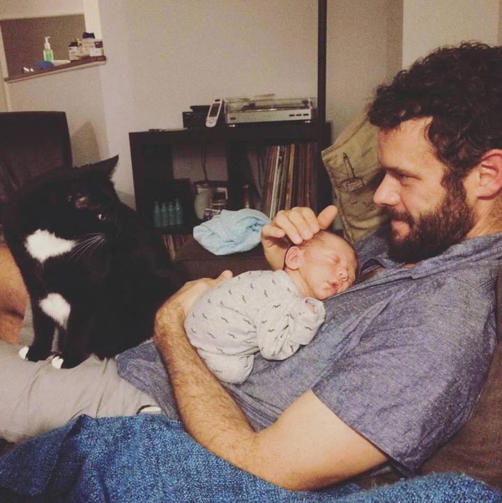 Natalie Stechyson's husband, Ian, holds their son and placates their cat.