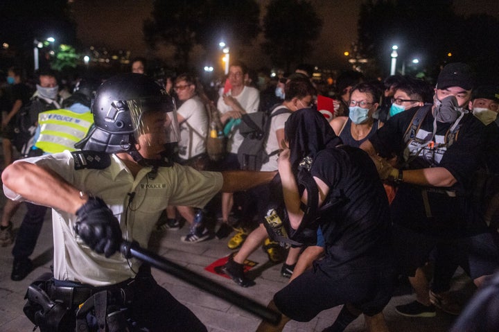 A police officer swings his baton as he restrains a protester during the clear up after the clash outside the Legislative Council in Hong Kong after a rally against a controversial extradition law proposal in Hong Kong on early June 10, 2019.