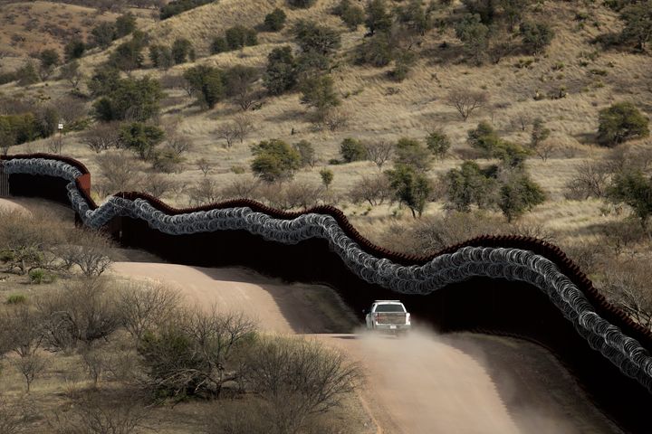This March 2, 2019, file photo, shows a Customs and Border Control agent patrolling on the US side of a razor-wire-covered border wall along the Mexico east of Nogales, Arizona.