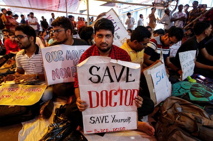 A doctor holds a placard at a government hospital during a strike demanding security.