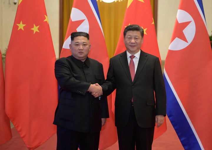 North Korean leader Kim Jong Un, left, and Chinese President Xi Jinping shake hands as they pose for a photo before talks at