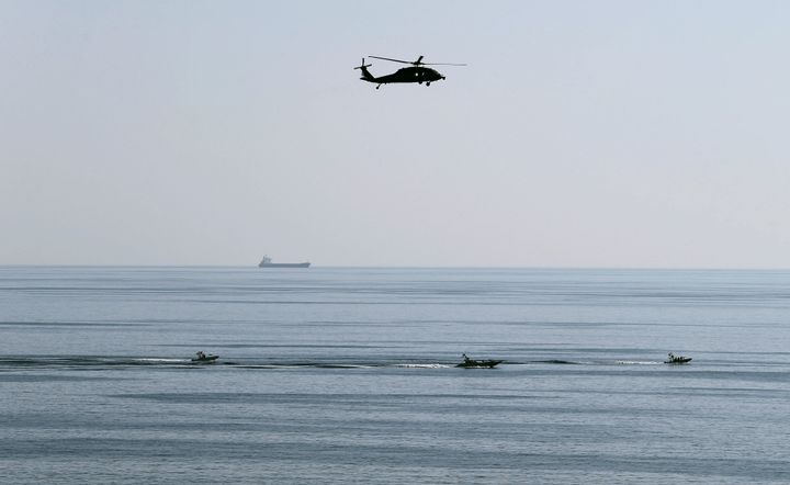 An MH-60S helicopter hovers over Iranian Revolutionary Guards speedboats which are seen near the USS John C. Stennis CVN-74 as it makes its way to gulf through strait of Hormuz, in 2018