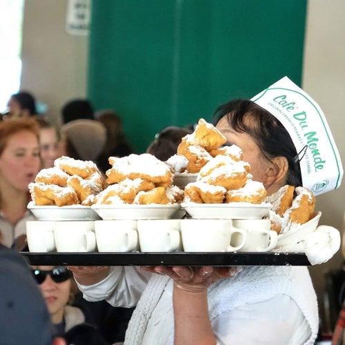 A server at New Orleans' legendary Cafe Du Monde carries a tray of coffee and fresh beignets.