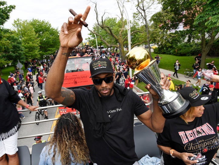 Kawhi Leonard points to the sky with a cigar in one hand and his NBA Finals MVP trophy in the other during the Raptors victory parade in Toronto on June 17, 2019.