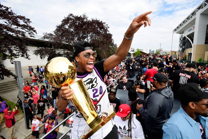 Kyle Lowry points to the crowd while smiling with the Larry O'Brien trophy in his hand during the Raptors parade in Toronto on June 17, 2019.