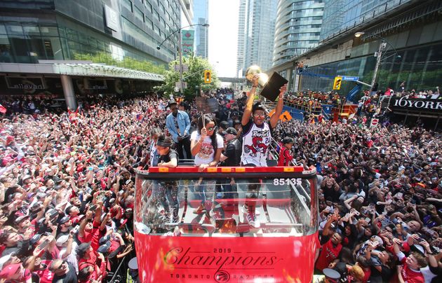 Kyle Lowry holds up the Larry O'Brien championship trophy as the parade bus makes its way through Toronto on June 18, 2019.