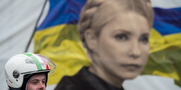 An anti-government protester stands in front of a portrait of jailed former Ukrainian Prime minister Yulia Tymoshenko, on Maidan square in Kiev, on February 13, 2014. Ukraine has been in chaos since November when President Viktor Yanukovych ditched an EU trade and political pact in favour of closer ties with Moscow, its former Soviet master. AFP PHOTO / MARTIN BUREAU (Photo credit should read MARTIN BUREAU/AFP/Getty Images)