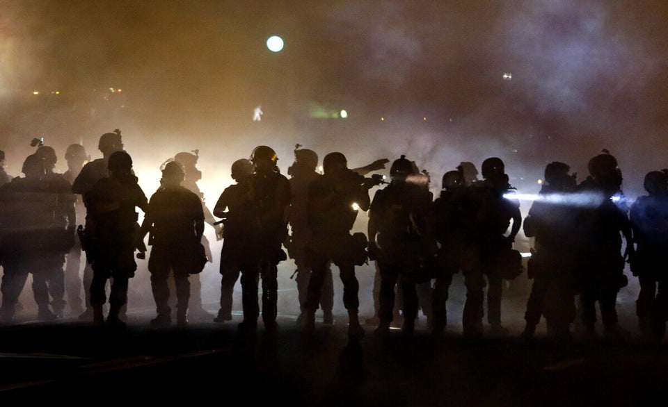 Police walk through a cloud of smoke as they clash with protesters