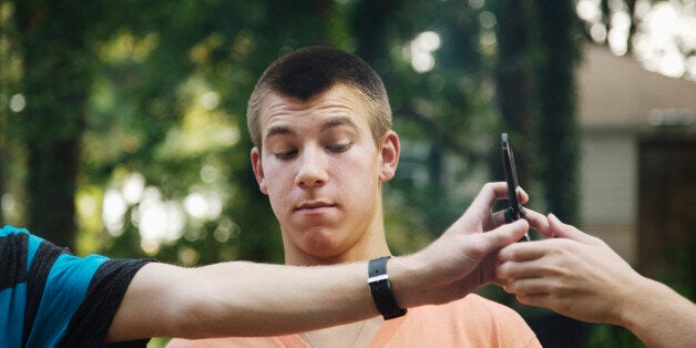 Teenager watching friends exchange cell phone