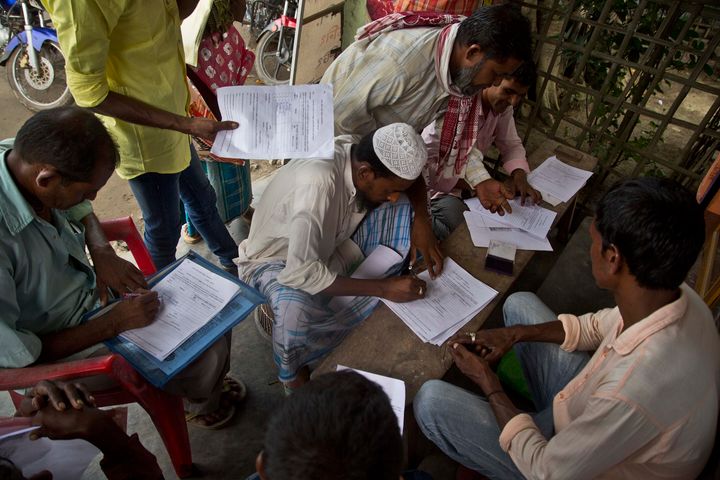 People whose names were left out in the National Register of Citizens (NRC) draft fill their forms to file appeals near a NRC center on the outskirts of Guwahati on 13 August 2018.