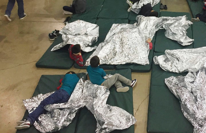 A June 17, 2018, file photo from U.S. Customs and Border Protection shows migrants being kept in a cage at a facility in McAllen, Texas. A year later, migrants still describe sleeping on floors under bright lights that shine 24/7, with nothing but Mylar blankets to keep warm.