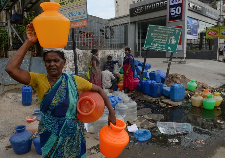 People wait to get water at a distribution point in Chennai.