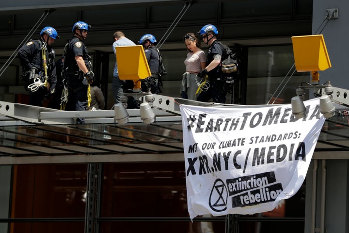 New York Police officers take into custody activists who climbed on the awning of the New York Times building to hang signs d