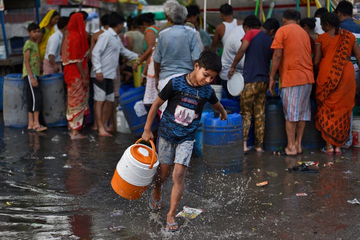 A boy carries a water container after filling it from a Delhi Jal Board tanker at Sanjay Colony in Okhla Phase II, on June 12, 2019 in New Delhi, India. 