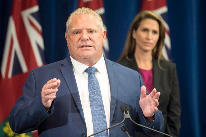 Ontario Premier Doug Ford speaks as former attorney general Caroline Mulroney looks on during an announcement at the Queen's Park Legislature in Toronto on Aug. 9, 2018.