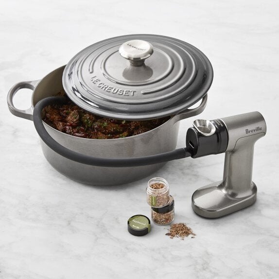 Breville's Smoking Gun imparts smoky flavor to food by ushering smoke into the cooking dish with a hose.