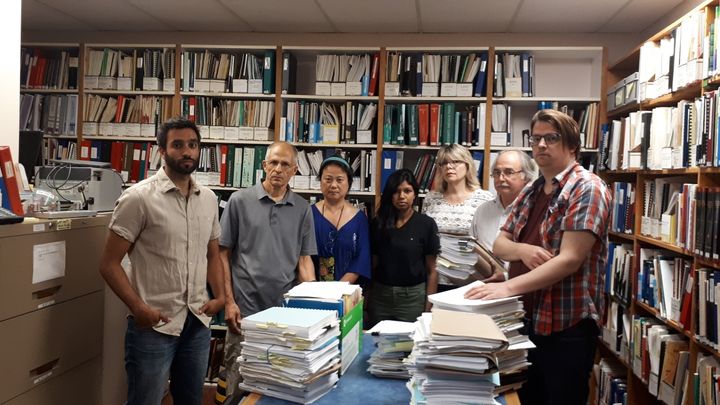 Staff at the Injured Workers Community Legal Clinic pose for a photo at their office. Each pile of documents relates to only one case, which staff says shows how complicated the law is around workers compensation.
