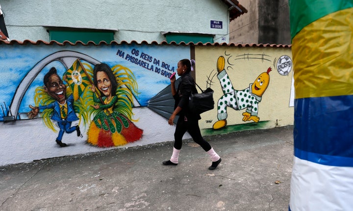 A woman walks past graffiti depicting Brazilian soccer superstars Pel&eacute;, left, and Marta, right, ahead of the 2014 Worl