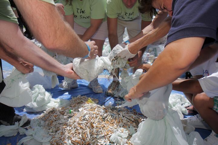 マイアミビーチで回収したタバコの吸い殻を、ゴミ袋に入れるボランティア