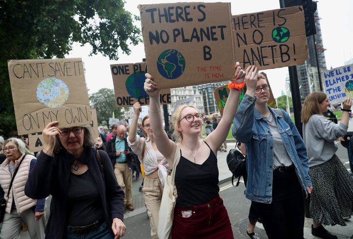 People carry placards as they attend a climate change demonstration in London.