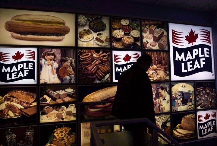 A Maple Leaf Foods employee walks past a company sign at its meat facility in Toronto, Mon. Dec. 15, 2008.
