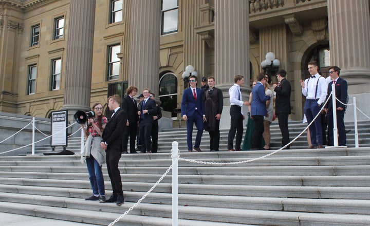 A student from a group taking grad photos walked down to stand next to a protester who was speaking through a megaphone. 