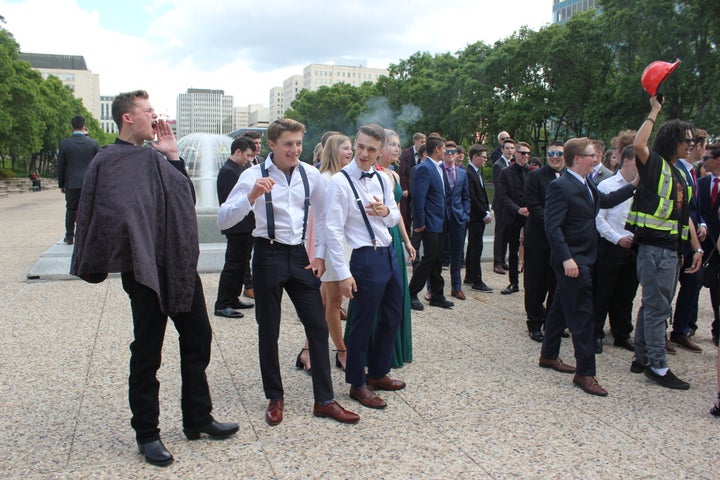 Graduating high school students yell at climate protesters gathered on Alberta's legislature grounds.