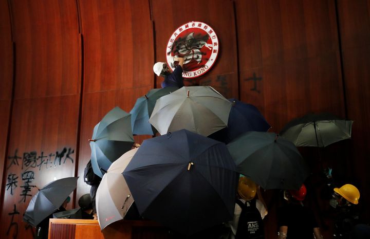 A person sprays paint over Hong Kong's coats of arms inside a chamber after protesters broke into the Legislative Council building.